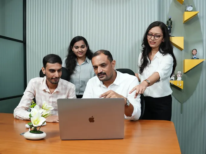 Wizard Infosys team collaborating around a laptop